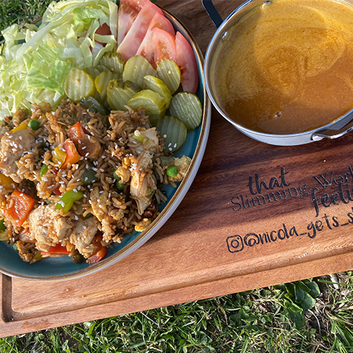 Chicken fried rice with curry sauce on chopping board outside