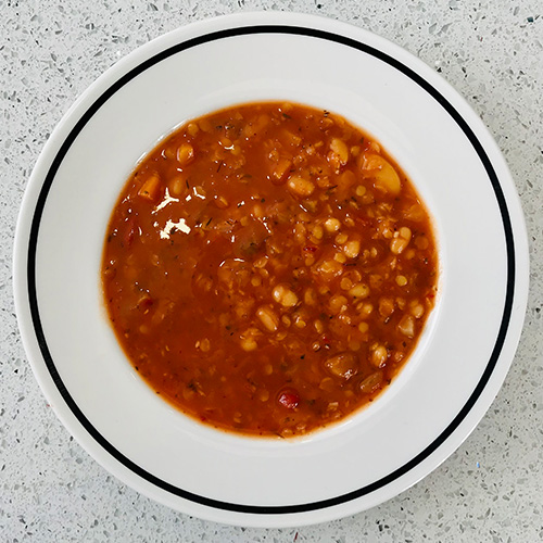 Bean and lentil Slimming World soup in a white bowl on a white kitchen counter top