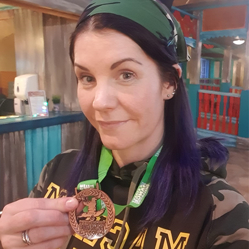 Emily holding her street dance medal, wearing camouflage jumper and headband