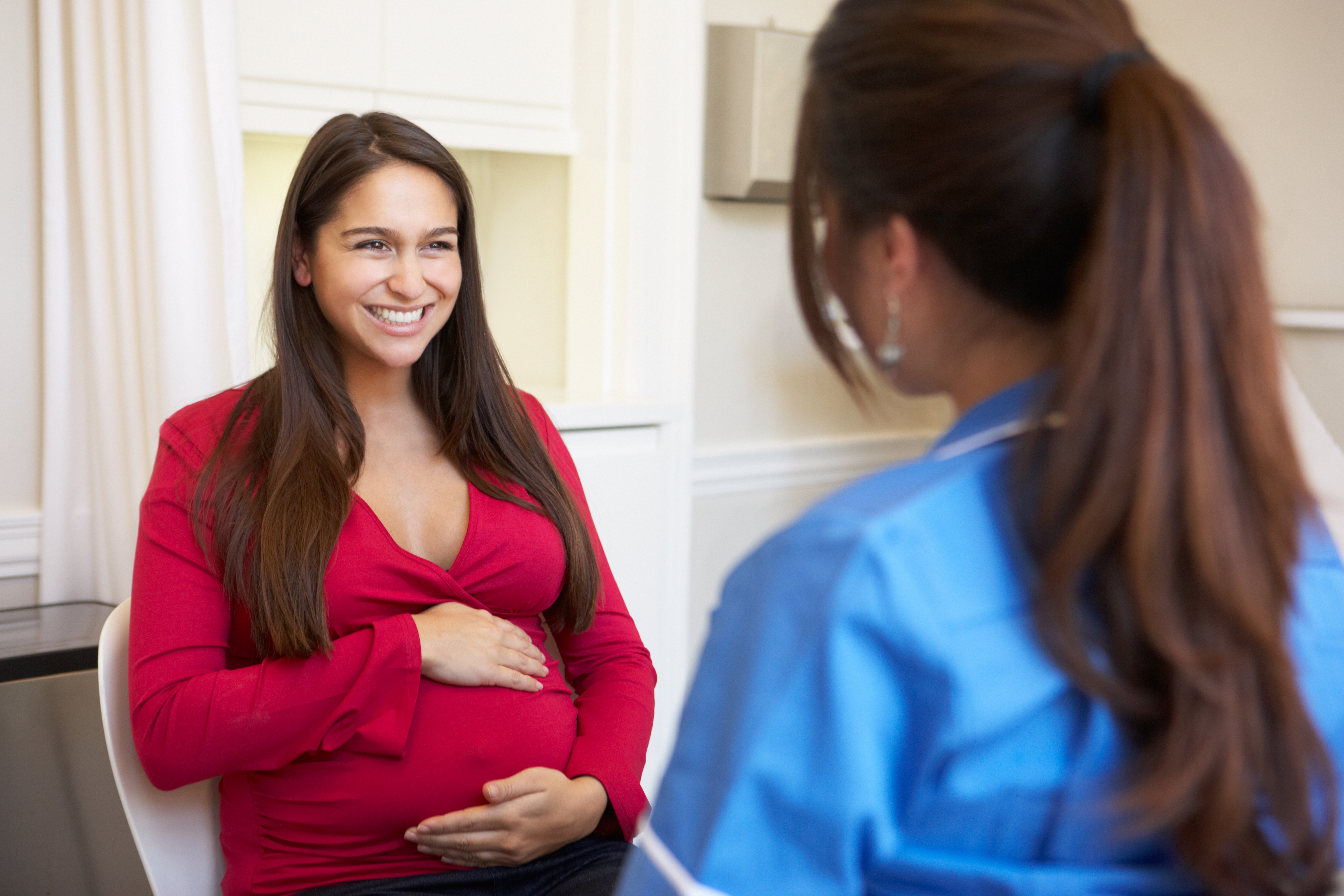 Happy pregnant woman talking to a nurse