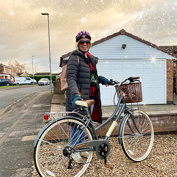 Slimming World member Amber standing with a bicycle. Gold starts falling from the sky.