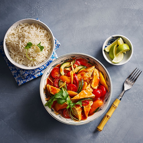 Slimming World Thai-style sweet and sour tofu in a white bowl with rice on the side on a light grey background