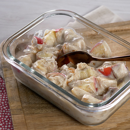 Apple pie Weetabix cheesecake in a glass container on a wooden chopping board