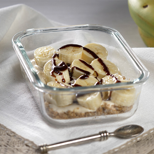 Banoffee Weetabix cheesecake in a glass container on a white cloth background