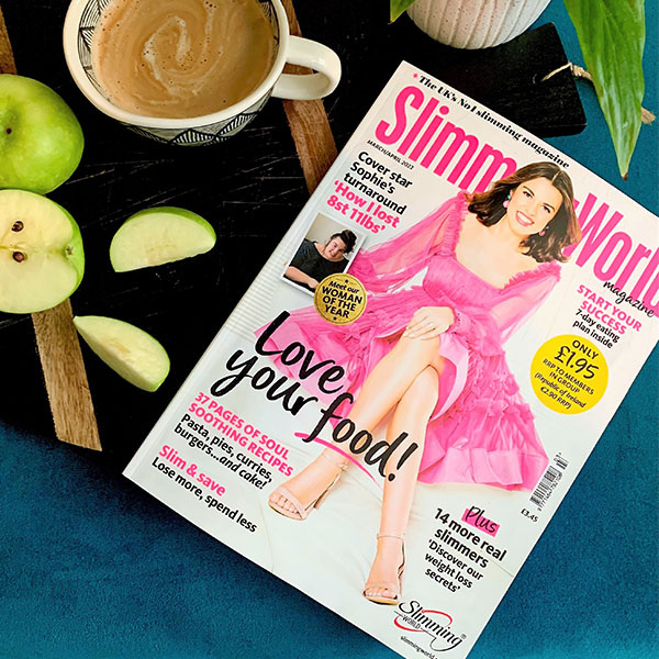 Slimming World Magazine on a coffee table with a sliced green apple and a mug of coffee
