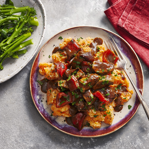 Smoky pork and pepper casserole on a white and red plate