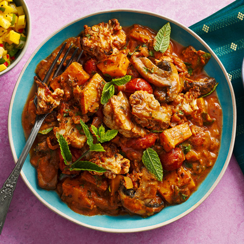 Slimming World cauliflower and mushroom rogan josh in a light blue bowl on a pink background