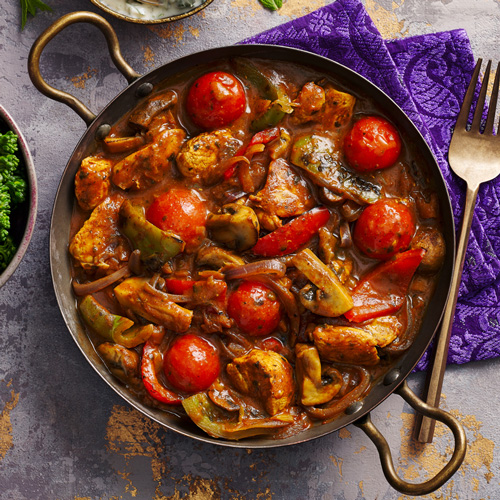 Slimming World chicken rogan josh in bronze pan on a purple background
