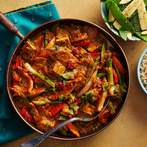 Slimming World tofu rogan josh in a bronze frying pan on an orange background