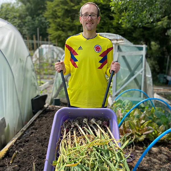 Phil Kayes pushing a wheelbarrow in allotment
