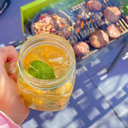 Louise's non-alcoholic Pimm's held above a smoking barbecue