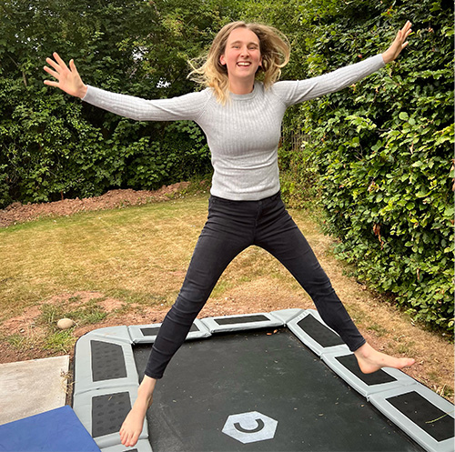 Member Meg jumping on a trampoline in the garden.