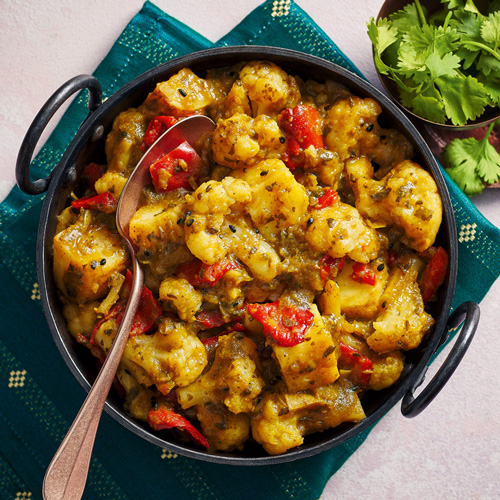 Slimming World aloo gobi in a grey pan on a blue background