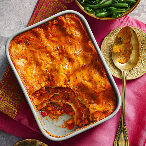 Slimming World chicken tikka lasagne in a white tray on a pink background