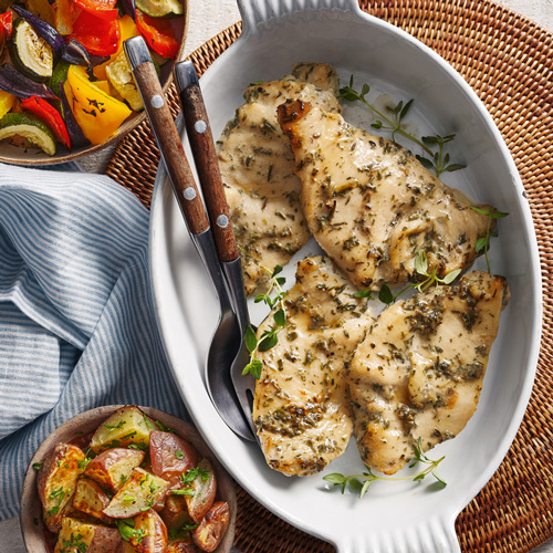 Slimming World garlic and herb chicken escalopes in a white pot on a brown background