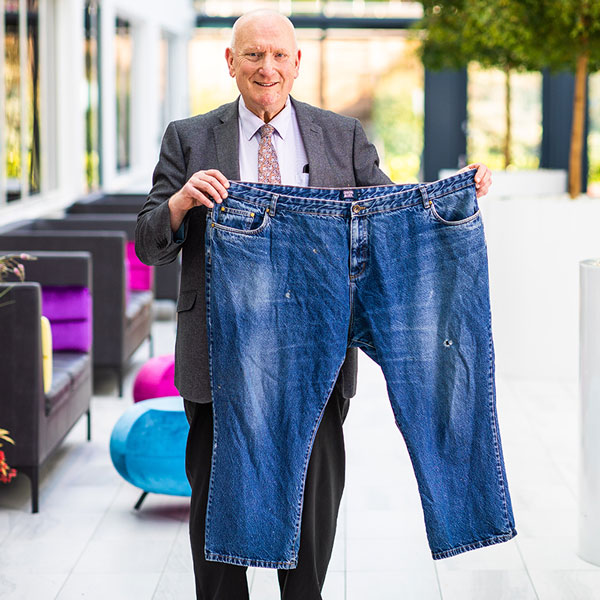 Slimming World member Greg holding up a large pair of jeans