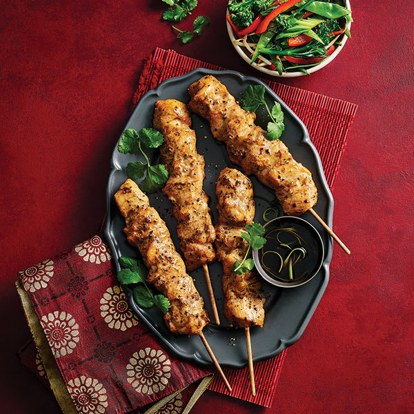 Slimming World salt and pepper chicken skewers served on a platter with a side dish of vegetables