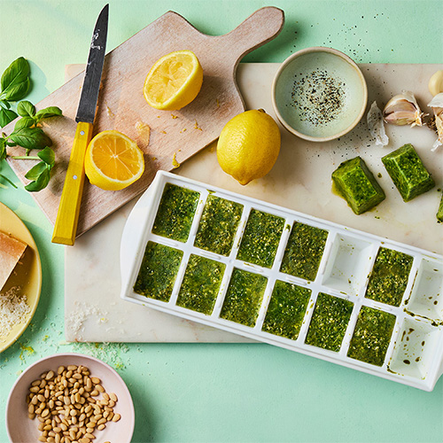 an ice cube tray filled with frozen homemade pesto
