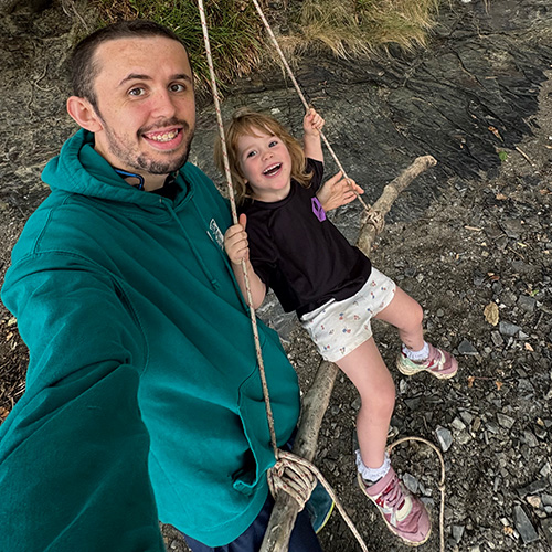 member Alex Lambert-Lee with daughter on a swing